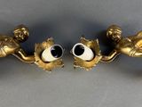 two gold figurines with eyes on them on a table
