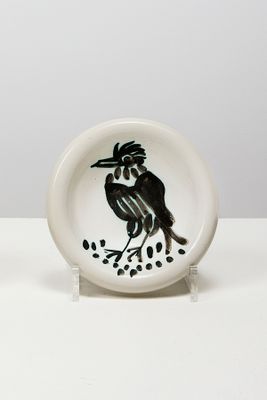 une petite assiette sur laquelle est représenté un oiseau, posée sur une table