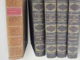several old books are lined up on a shelf next to each other