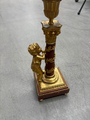 un bougeoir doré et rouge orné d'un petit garçon