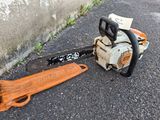 a chainsaw that is laying on the ground next to a piece of wood