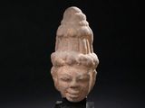 an ancient stone head of a woman on a black stand