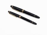 une paire de stylos à plume noirs et dorés posés sur une surface blanche