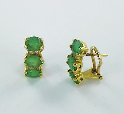 une paire de boucles d'oreilles en or et pierres vertes sur fond blanc