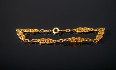 gros plan d'un bracelet en or sur une surface noire