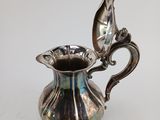 an image of a silver pitcher with a spoon in it