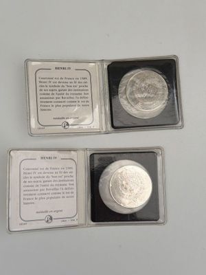 two silver coins are in a box on a white surface