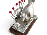 a silver sculpture of a dog with red balls on it