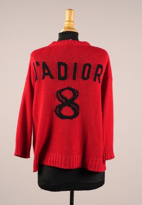 un pull rouge avec des lettres noires et un serpent dessiné dessus