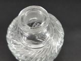 a clear glass vase with a silver lid on a black surface
