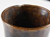 a close up of a brown cup on a white table