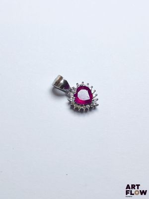 une photo d'un pendentif orné d'un diamant rose et blanc, posé sur une surface blanche
