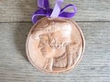 a bronze medal with a purple ribbon on a wooden table