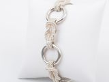 a close up of a silver bracelet on a white pillow
