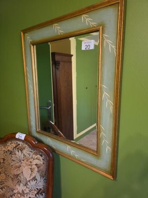 un miroir accroché au mur à côté d'une chaise dans une pièce