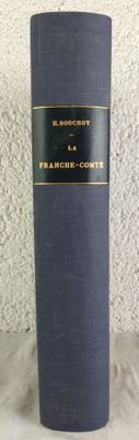 un vieux livre posé sur une table à côté d'un mur blanc