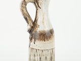 a brown and white vase with a handle on a white background
