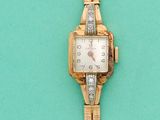 une montre en or et un bracelet en or posés sur une surface verte