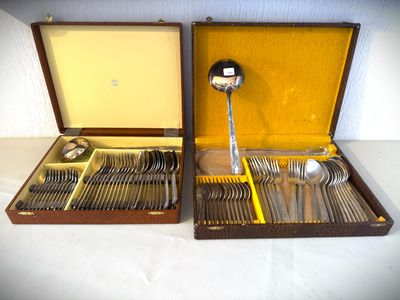 deux sets d'argenterie dans un coffret sur une table