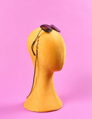 tête de mannequin jaune portant des lunettes de soleil sur fond rose