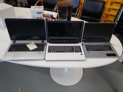 three laptops that are sitting on a white table
