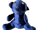 a blue teddy bear sitting on a white surface