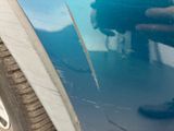 a close up of a person ' s hand on the side of a blue car