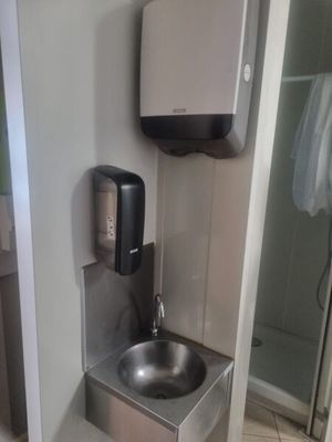 une salle de bains équipée d'un lavabo et d'un sèche-mains fixé au mur