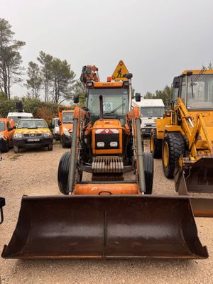 a tractor that is parked in a lot with other vehicles behind it