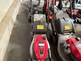 Plusieurs tondeuses à gazon sont alignées en rang dans un garage
