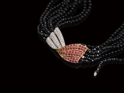 un gros plan sur un collier de perles noires orné de pierres roses et blanches