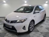 La Toyota Corolla blanche est garée dans une pièce au sol à carreaux.