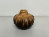 un petit vase brun posé sur une surface blanche