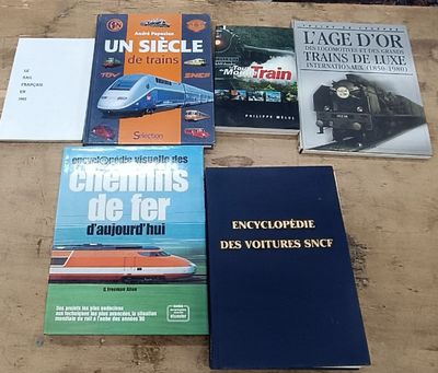 several books on a table with a train in the background