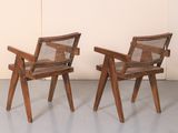 two wooden chairs sitting next to each other in a room