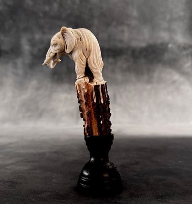 a statue of an elephant standing on a tree stump