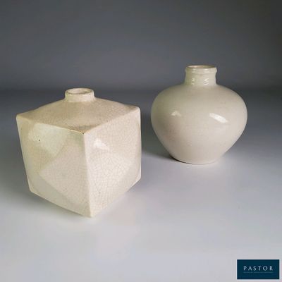 deux vases blancs posés l'un à côté de l'autre sur une table