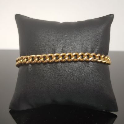 un bracelet en chaîne d'or posé sur un coussin noir