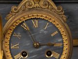 a gold clock sitting on top of a marble table