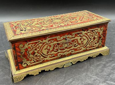 une boîte rouge et dorée posée sur une surface grise