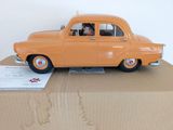 une petite voiture orange posée sur une boîte en carton