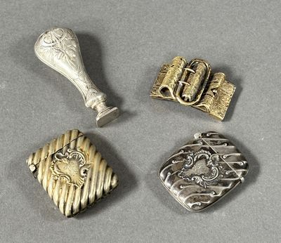 trois bijoux en argent et en or posés sur une surface grise