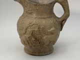 a brown vase with a bird on it on a white surface