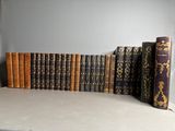 Plusieurs vieux livres sont alignés sur une étagère devant un mur gris.