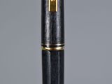 a close up of a pen on a table with a gray background