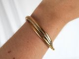 the arm of a woman wearing a gold bracelet and a gold ring