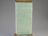 une image représentant un vase vert posé sur un socle en bois