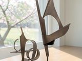 two sculptures sitting on a wooden table in front of a window