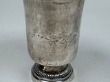 an antique silver cup with a metal base on a white surface