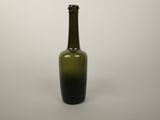 a green glass bottle sitting on a white surface